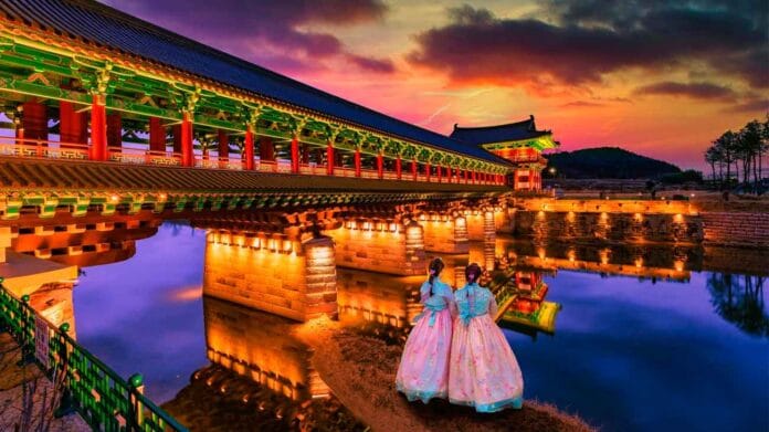 mas-importante-gyeongju-lugares-imprescindibles-ver Puente Woljeonggyo iluminado al atardecer en Gyeongju, Corea del Sur, con dos mujeres en hanbok tradicional