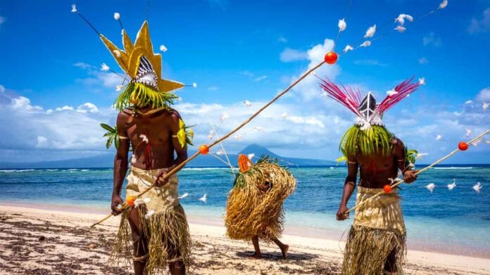 Danzantes tradicionales en la playa de Vanuatu con el volcán Yasur al fondo